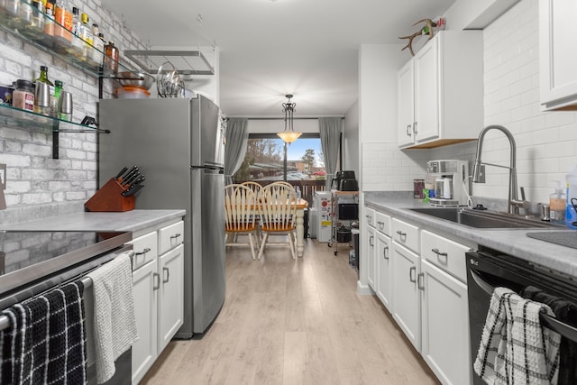 kitchen featuring backsplash, stainless steel appliances, light wood finished floors, and a sink