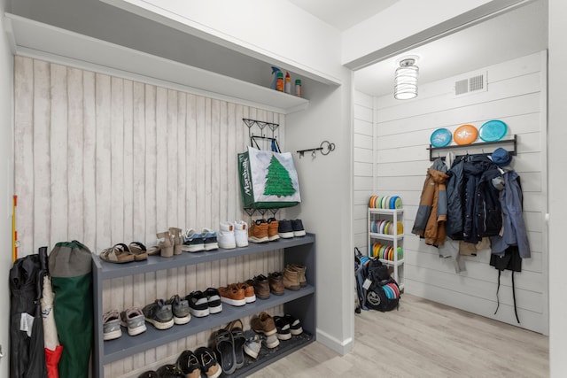 mudroom with wooden walls, wood finished floors, and visible vents