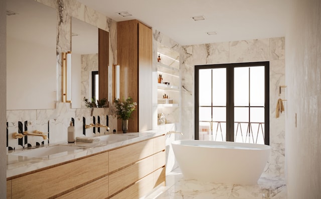 full bath with plenty of natural light, a soaking tub, double vanity, marble tiled floors, and tile walls