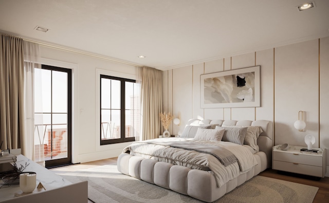 bedroom with wood finished floors, ornamental molding, and a decorative wall