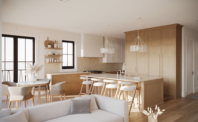 kitchen with backsplash, a kitchen bar, a kitchen island with sink, decorative light fixtures, and open shelves