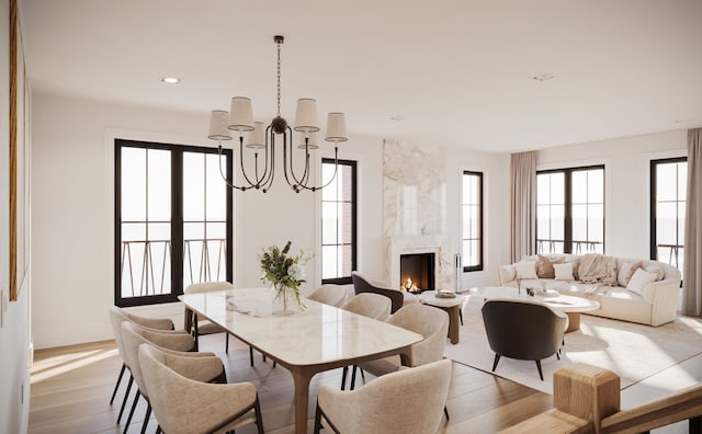 dining room with a chandelier, wood finished floors, a high end fireplace, and baseboards