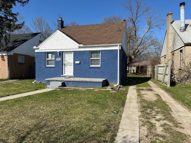 bungalow with brick siding, driveway, a front yard, and fence