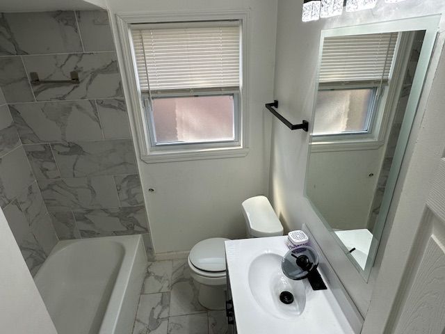 bathroom featuring a sink, marble finish floor, shower / bath combination, baseboards, and toilet