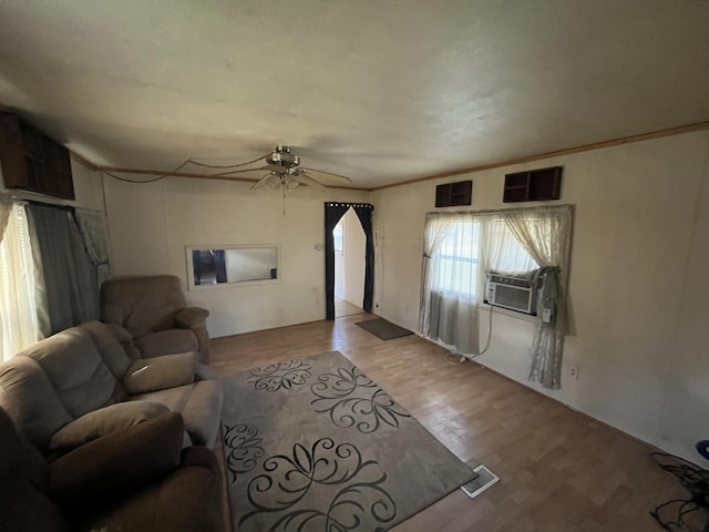 living room with a ceiling fan, wood finished floors, cooling unit, and visible vents
