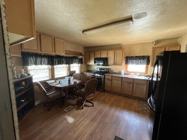 kitchen featuring a textured ceiling, a wealth of natural light, and black appliances