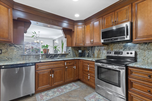 kitchen with stainless steel appliances, a sink, brown cabinetry, and tasteful backsplash