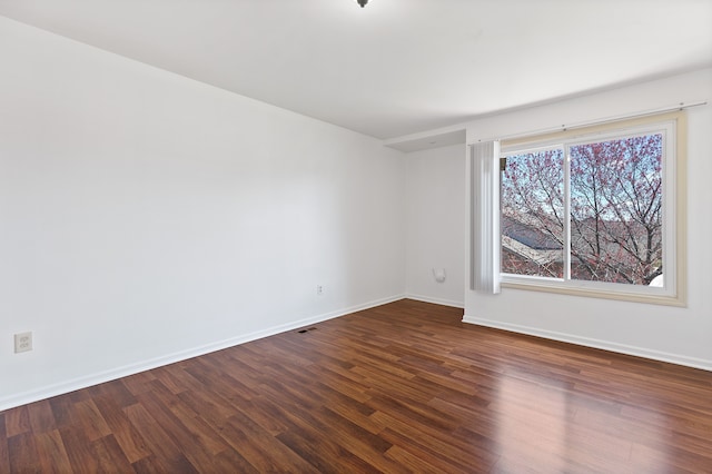unfurnished room featuring baseboards, visible vents, and dark wood-style floors