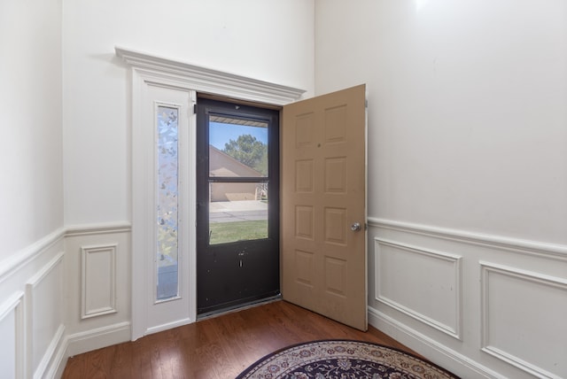 entryway with wood finished floors, a decorative wall, and wainscoting