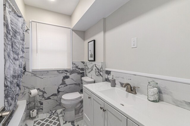 8911 Plainview Ave, Detroit, MI 48228 - bathroom with marble finish floor, a wainscoted wall, toilet, vanity, and tile walls