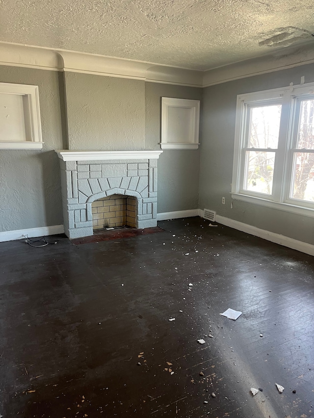 unfurnished living room featuring baseboards, a stone fireplace, visible vents, and a textured ceiling