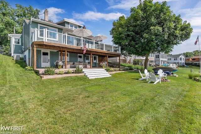 rear view of property featuring a lawn, a wooden deck, and a patio area