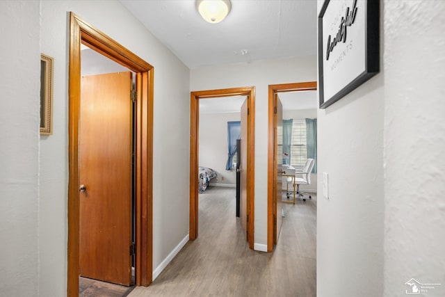 corridor with baseboards and wood finished floors