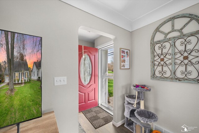 foyer featuring arched walkways, wood finished floors, and baseboards