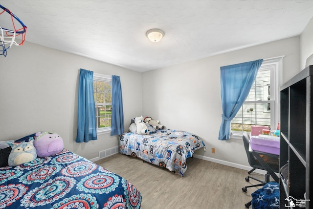 bedroom with wood finished floors, visible vents, and baseboards