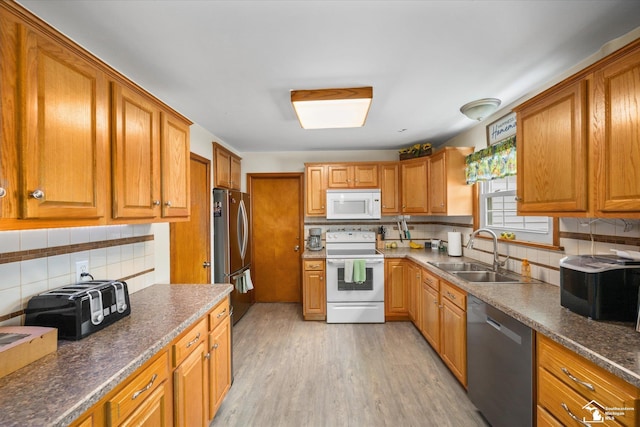 kitchen with stainless steel appliances, a toaster, a sink, light wood-type flooring, and decorative backsplash
