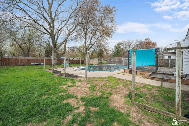 view of pool with a lawn, a fenced backyard, an outbuilding, a wooden deck, and a storage unit