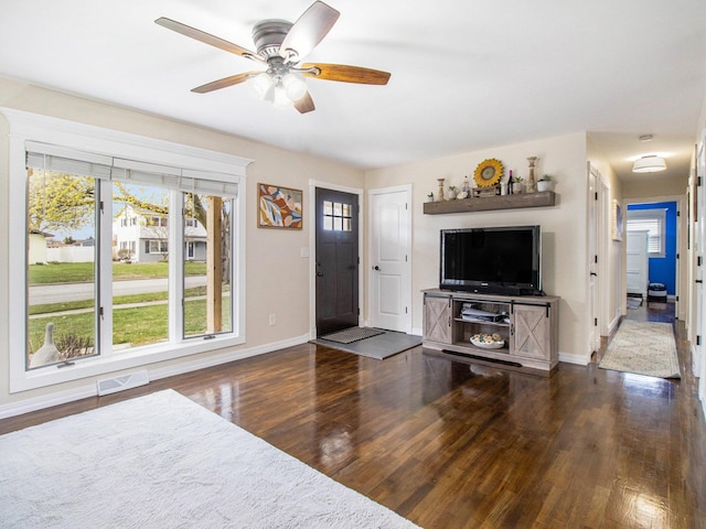 living area with baseboards, wood finished floors, visible vents, and ceiling fan