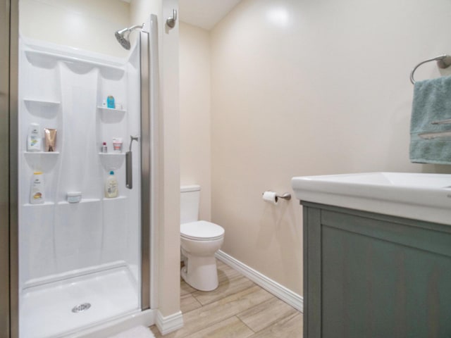 full bath featuring wood finished floors, vanity, toilet, and a stall shower