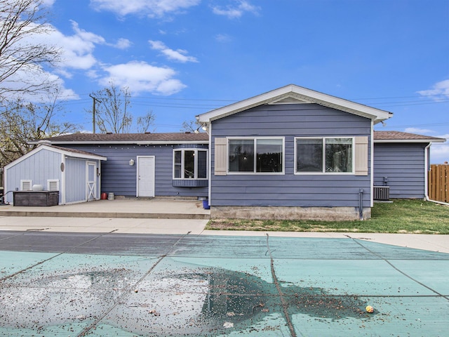 back of house with fence, an outbuilding, cooling unit, a covered pool, and a storage unit
