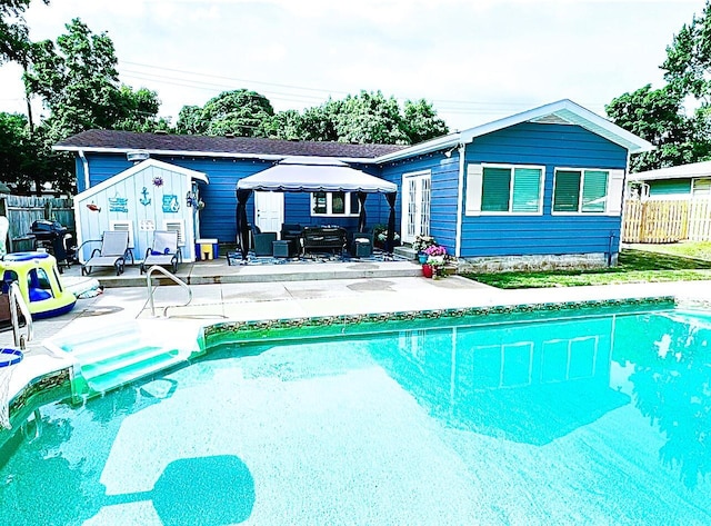 view of swimming pool with a fenced in pool, fence, entry steps, an outdoor structure, and a patio