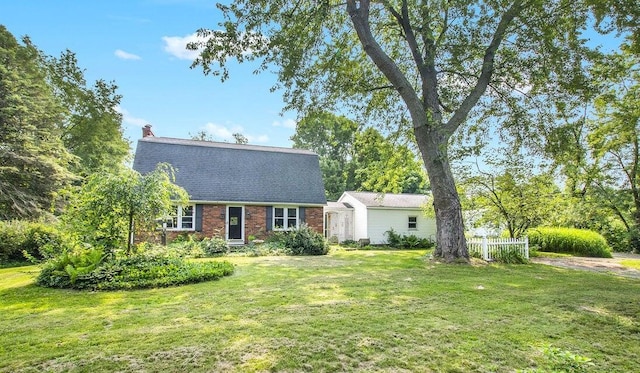 colonial inspired home with a front lawn, brick siding, and a chimney