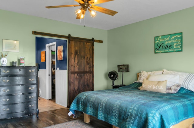 bedroom featuring a barn door, wood finished floors, and ceiling fan