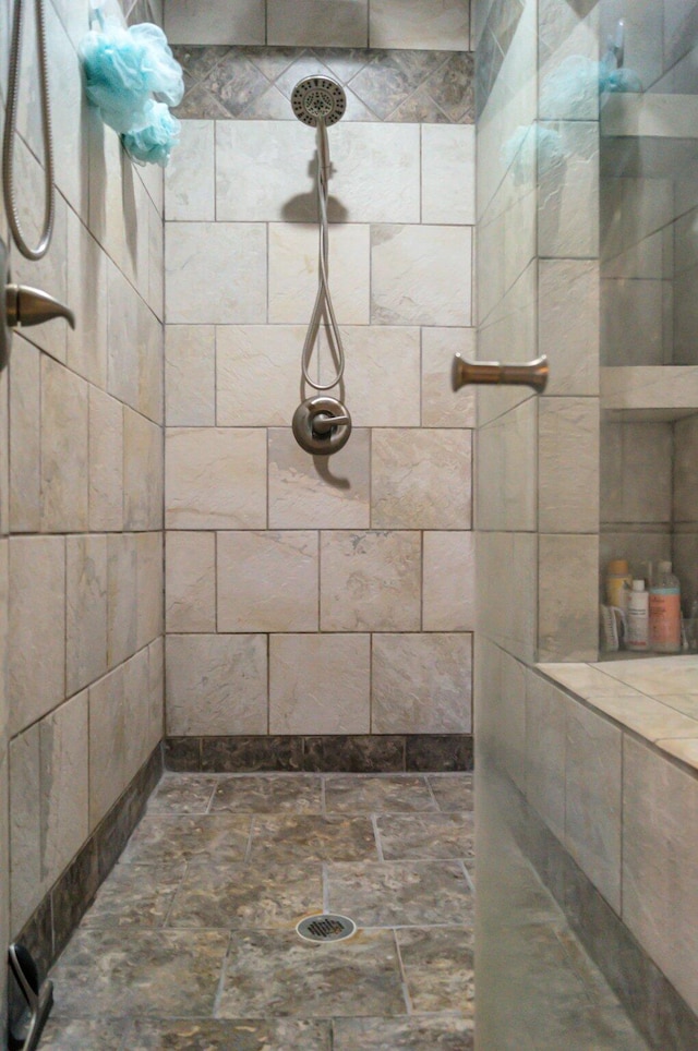 bathroom with stone finish flooring and a tile shower