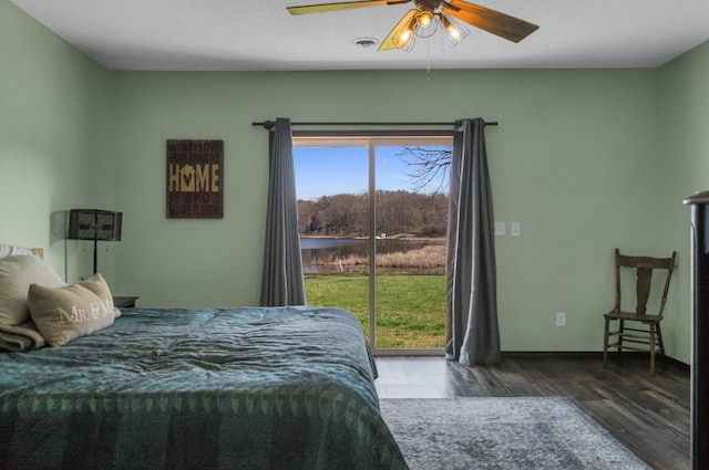 bedroom with wood finished floors, a water view, a ceiling fan, visible vents, and baseboards