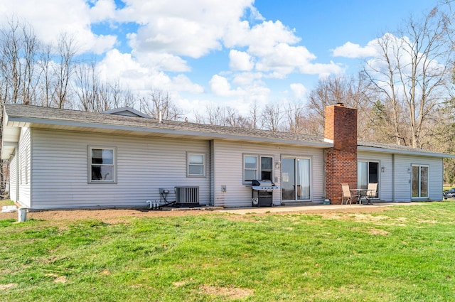 rear view of house with a lawn, a chimney, central AC, and a patio