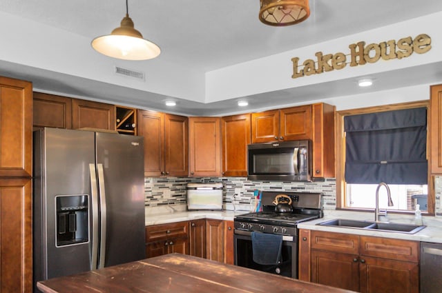 kitchen with stainless steel appliances, light countertops, visible vents, a sink, and decorative backsplash
