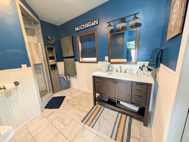 bathroom featuring wainscoting, vanity, and a shower stall