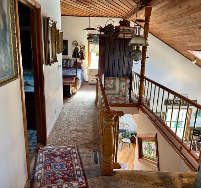 hall with wood ceiling, visible vents, and carpet