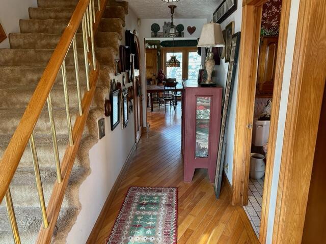 hallway featuring stairway, baseboards, and light wood-style flooring