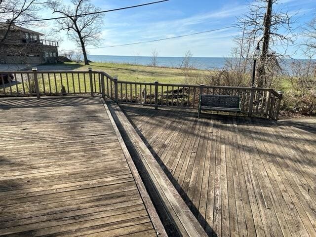 wooden terrace featuring a water view and a yard