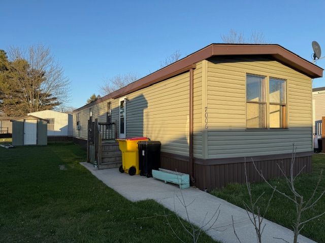 7006 Brides Bay Ct, Ira, MI 48023 - view of home's exterior with an outdoor structure, a yard, and a storage unit