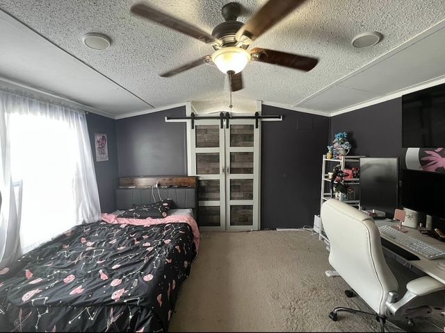 7006 Brides Bay Ct, Ira, MI 48023 - bedroom with a ceiling fan, a textured ceiling, vaulted ceiling, a barn door, and carpet floors