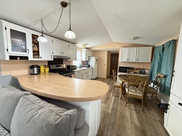 7006 Brides Bay Ct, Ira, MI 48023 - kitchen featuring built in microwave, stainless steel range with gas cooktop, freestanding refrigerator, wood finished floors, and lofted ceiling