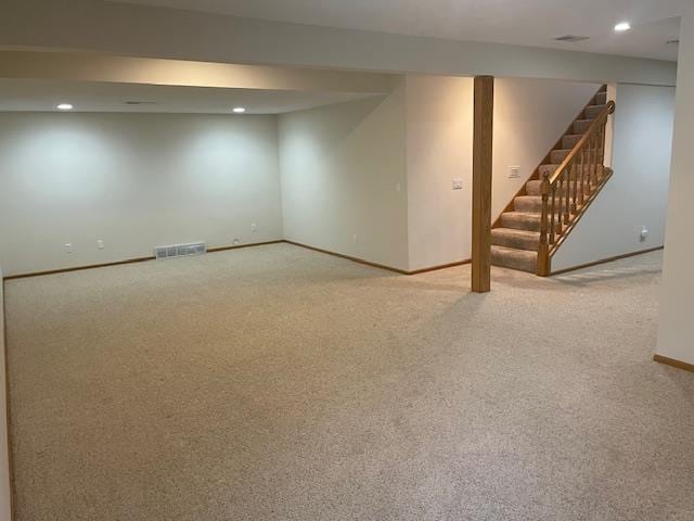 finished below grade area featuring baseboards, carpet flooring, stairs, and visible vents