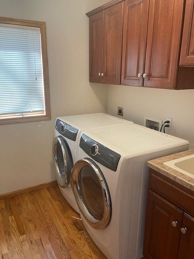washroom featuring washing machine and dryer, light wood-style flooring, baseboards, and cabinet space