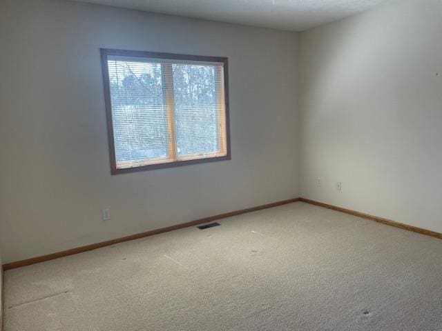 unfurnished room with light carpet, visible vents, and baseboards