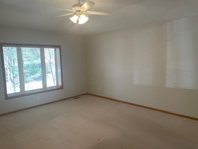 spare room featuring visible vents, light carpet, a ceiling fan, and baseboards