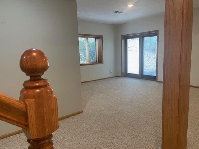 carpeted spare room featuring visible vents and baseboards