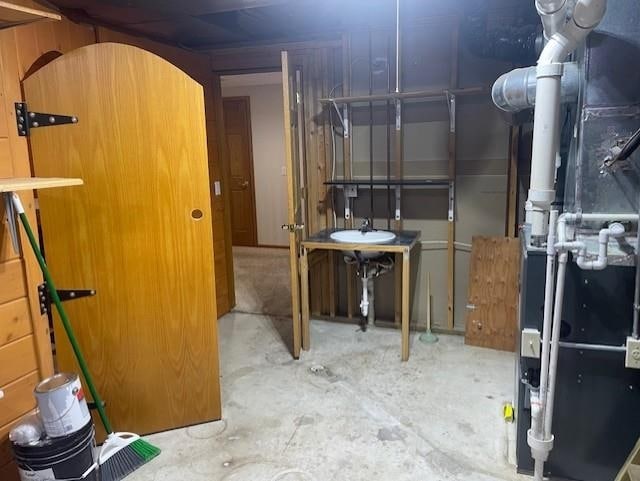unfinished basement featuring heating unit and a sink