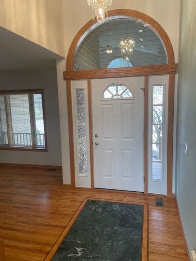 entryway with wood finished floors, visible vents, baseboards, and an inviting chandelier