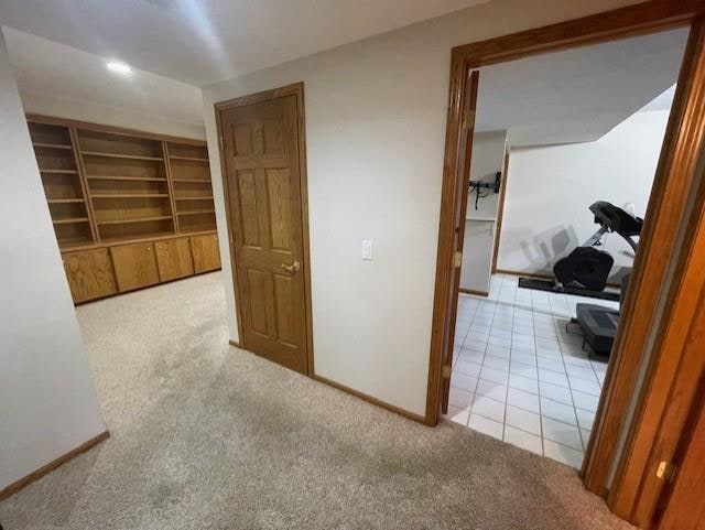 corridor featuring baseboards, tile patterned floors, and carpet