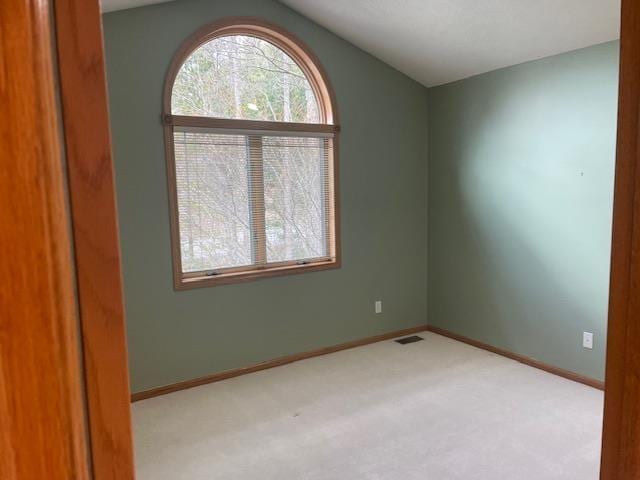 empty room featuring lofted ceiling, baseboards, visible vents, and carpet floors