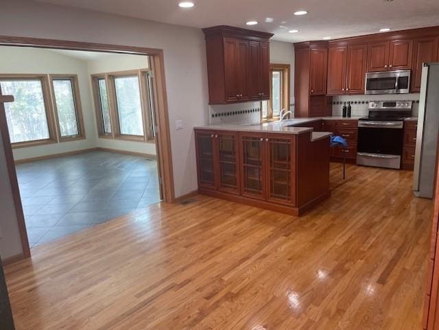 kitchen featuring light countertops, backsplash, baseboards, appliances with stainless steel finishes, and recessed lighting