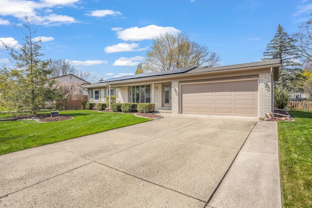 ranch-style house featuring a front lawn, brick siding, a garage, solar panels, and driveway