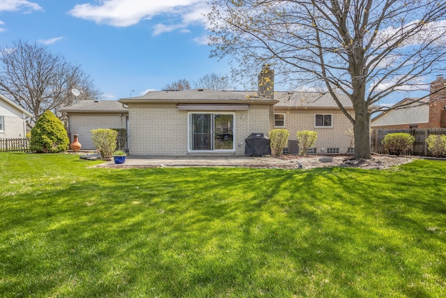 back of property featuring brick siding, a patio, fence, and a lawn